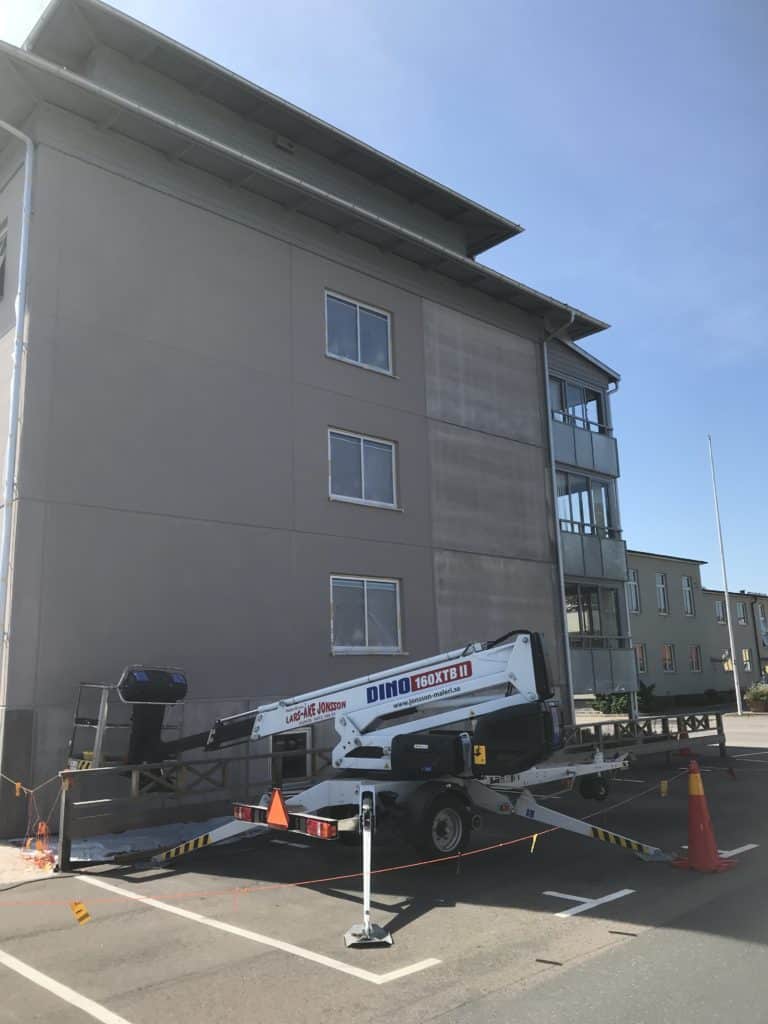 Fasadmålning av flerbostadshus med skylift